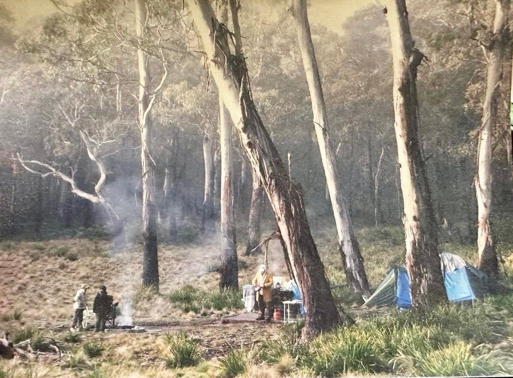 landscape image of Australia bush with tents, 3 men with a fire on