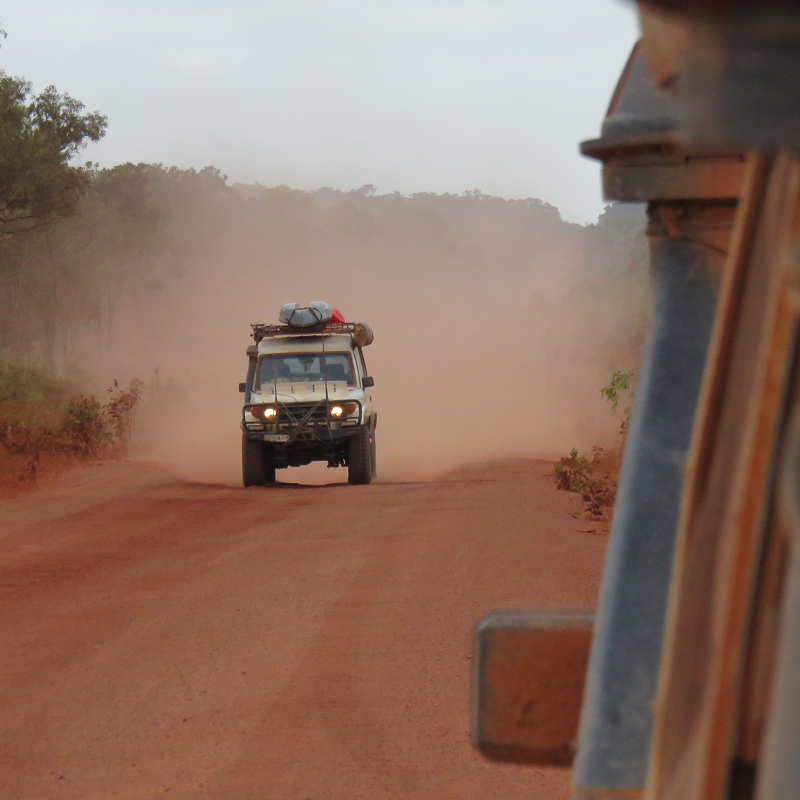 four wheel drive driving on a sandy track with dust behind the car